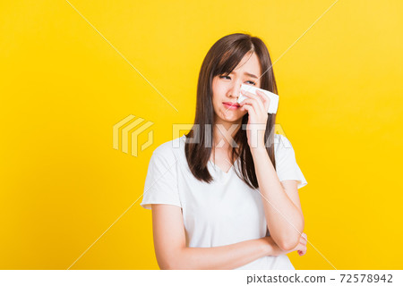 Woman sad she crying wiping tears from eyes with a tissue Woman sad she crying wiping tears from eyes with a tissue 72578942