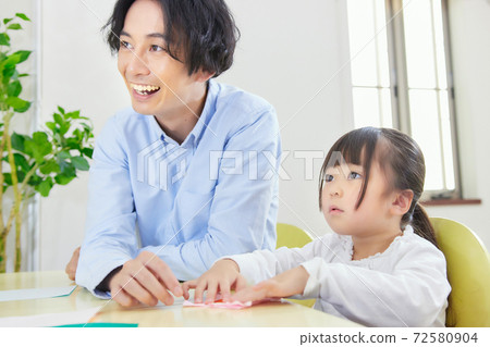 Dad and girl happily origami in the living room 72580904