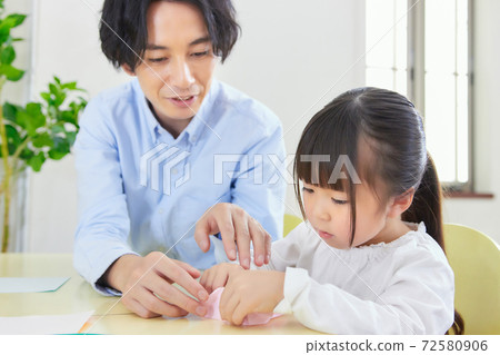 Dad and girl happily origami in the living room 72580906