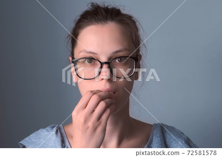 Woman in glasses pretending she is eating looking at camera on grey background. 72581578