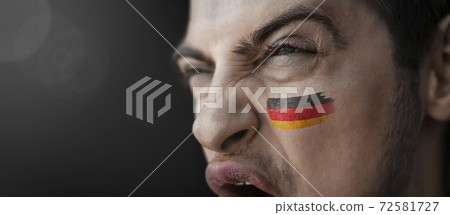 A screaming man with the image of the country's national flag on his face 72581727