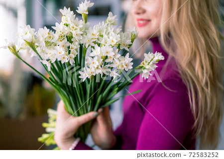 a florist girl holding a bouquet of narcissus. Floral shop 72583252