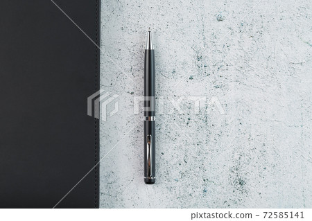 Black Notepad with a black pen on a gray background Black Notepad with a black pen on a gray background 72585141