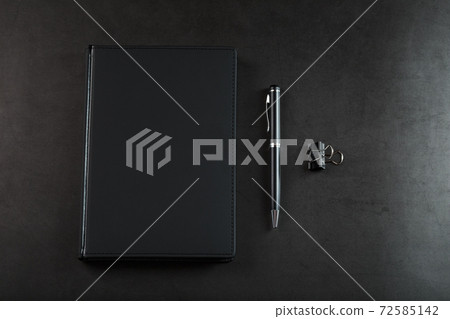 Black Notepad with a black pen on a black background. Black Notepad with a black pen on a black background. 72585142