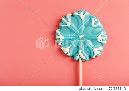 Blue Lollipop in the shape of a snowflake on a pink background. Blue Lollipop in the shape of a snowflake on a pink background. 72585143