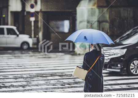 People waiting for a traffic light on a rainy pedestrian crossing People waiting for a traffic light on a rainy pedestrian crossing 72585215