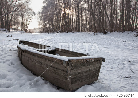 Old boat on the lake covered with snow in winter 72586714