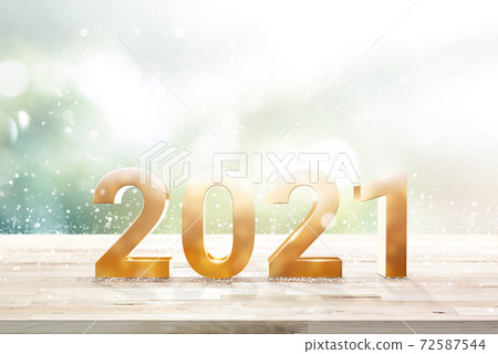 Shiny golden 2021 number on wood table top with bright green bokeh andsnowfall 72587544