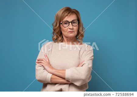 Serious elderly caucasian woman in glasses with folded hands. Serious elderly caucasian woman in glasses with folded hands. 72588694
