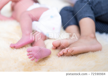 Closeup newborn baby feet and older brother feet sleeping on bed 72590984
