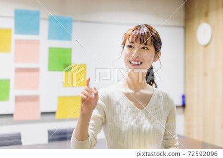 一個女人在會議室的透明板上貼彩色貼紙 一個女人在會議室的透明板上貼彩色貼紙 72592096