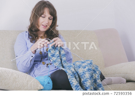 Woman knitting a scarf at home 72593356
