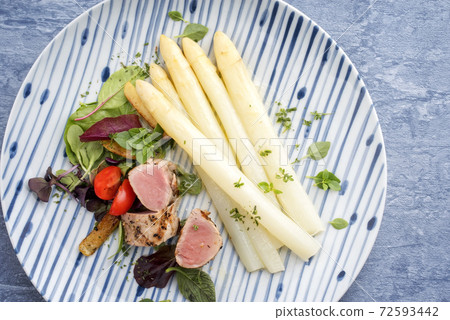 Modern style sliced pork fillet steak with white asparagus salad and roast potatoes  72593442