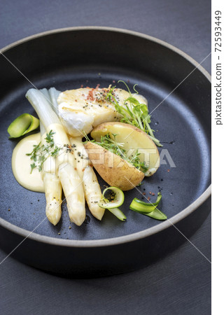 German fried cod fish filet with white asparagus in sauce hollandaise und roast potatoes German fried cod fish filet with white asparagus in sauce hollandaise und roast potatoes 72593449