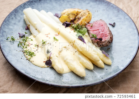 dry aged sliced fillet steak with white asparagus in hollandaise sauce and roast potatoes dry aged sliced fillet steak with white asparagus in hollandaise sauce and roast potatoes 72593461