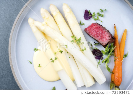 barbecue dry aged sliced filet steak with white asparagus and sauce hollandaise  72593471