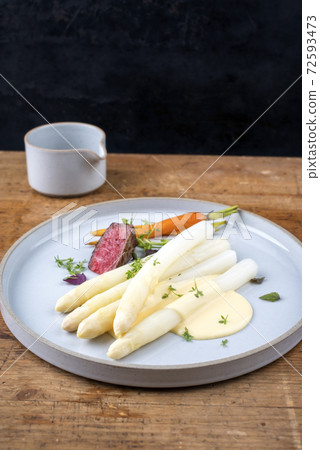 barbecue dry aged sliced filet steak with white asparagus and sauce hollandaise  72593473