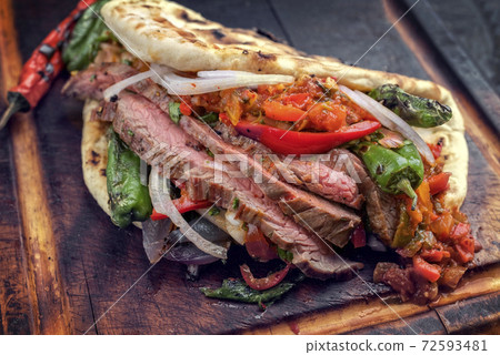 barbecue dry aged wagyu flank steak with chili relish and vegetable in a flatbread  72593481