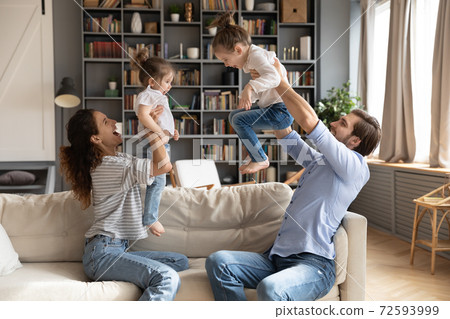 Happy parents play with excited little daughters 72593999