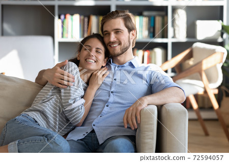 Happy couple relax on sofa hugging and dreaming 72594057