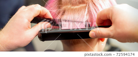 Hairdresser straightening short pink hair 72594174