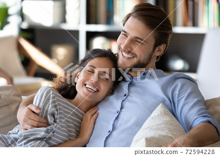 Happy young couple relax on couch hugging 72594228
