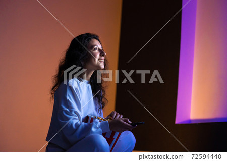 person watches a movie sitting on the couch with a bucket of popcorn 72594440