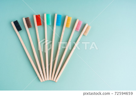 A set of Eco-friendly antibacterial toothbrushes made of bamboo wood on a light green background. Environmental care trends 72594659