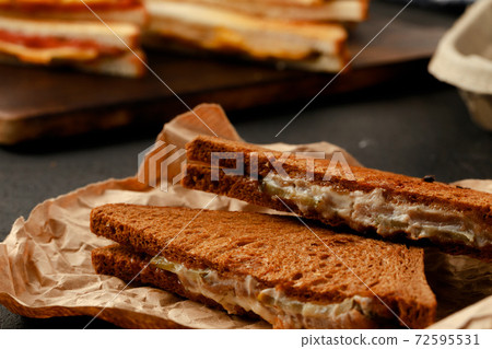 Toasted rye sandwich with ham cut into halves on table 72595531