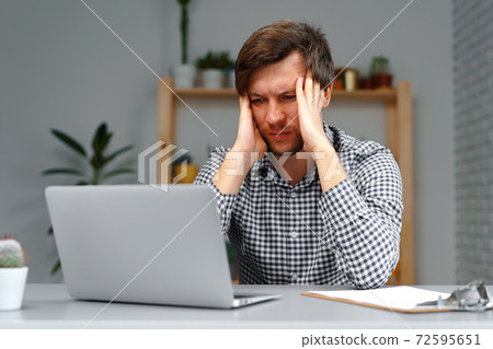 Young man working on laptop at his working table 72595651