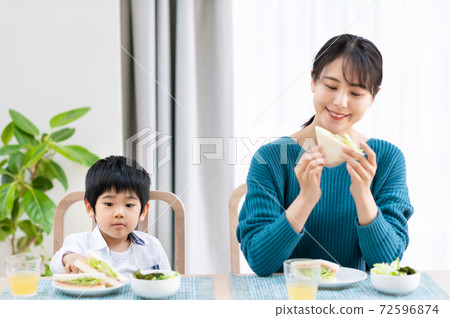 母親和男孩在桌旁吃 72596874
