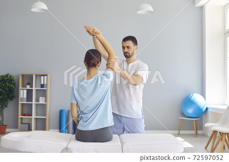 Young man doctor chiropractor or osteopath fixing woman patient arms joints during visit Young man doctor chiropractor or osteopath fixing woman patient arms joints during visit 72597052