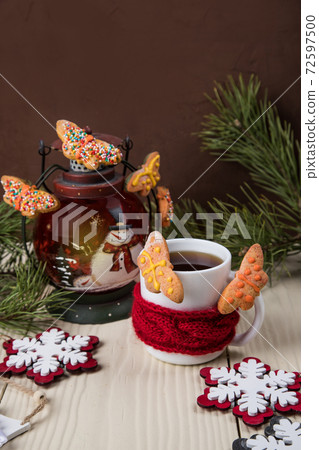 A Cup of tea in a red scarf with homemade butterfly cookies with Christmas decor. Close-up, copy space 72597500