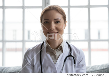 Friendly woman physician looking at web camera consulting patient online Friendly woman physician looking at web camera consulting patient online 72598540