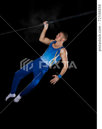 Muscular male gymnast training in gym, flexible and active. Caucasian fit guy, athlete in blue sportswear isolated on black 72598856