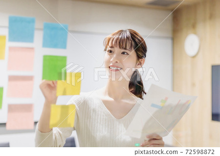 A woman having a meeting using a transparent board in a conference room A woman having a meeting using a transparent board in a conference room 72598872
