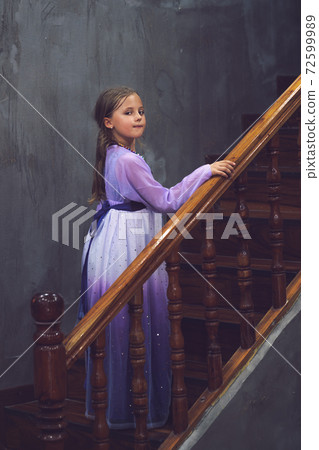 Caucasian girl in a pink purple dress posing on wooden stairs 72599989