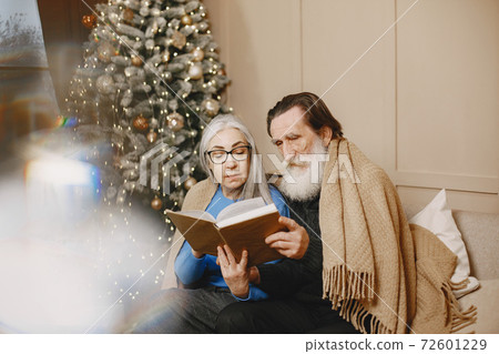 Senior couple with book near the Christmas tree Senior couple with book near the Christmas tree 72601229