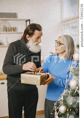 Senior couple with gifts near the Christmas tree Senior couple with gifts near the Christmas tree 72601236
