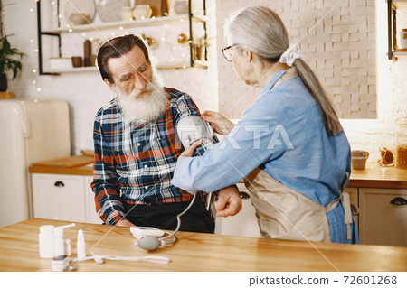 Senior woman and man at home meassure blood pressure 72601268