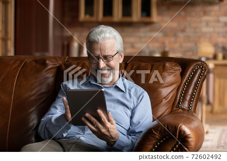 Happy senior man in glasses using digital computer tablet. 72602492