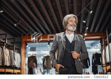 Senior man choosing a new suit in a store 72602622