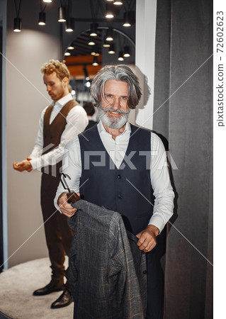 Senior man choosing a new suit in a store 72602623