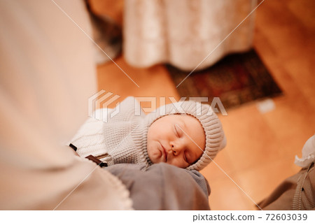 newborn baby in the arms of his mother during the service in the church. newborn baby in the arms of his mother during the service in the church. 72603039