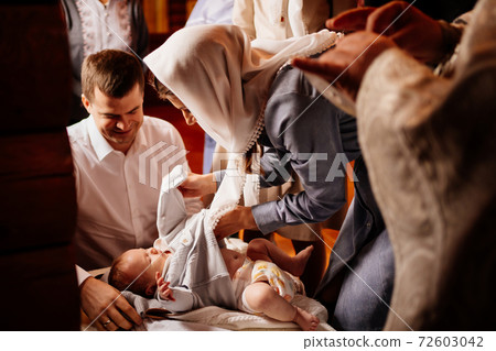 parents dress their child in the Church on a table. the ordinance of baptism. parents dress their child in the Church on a table. the ordinance of baptism. 72603042