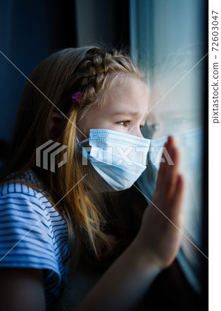little girl in protective mask, look out of window outside. self-isolating. little girl in protective mask, look out of window outside. self-isolating. 72603047