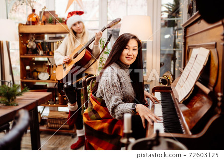 two young women play the piano and guitar in a country house. two young women play the piano and guitar in a country house. 72603125