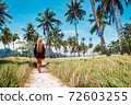 Rear view of a beautiful young woman surrounded by tropical landscape 72603255