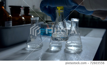 Hand and flask with liquid. Hand and flask with liquid. 72603556
