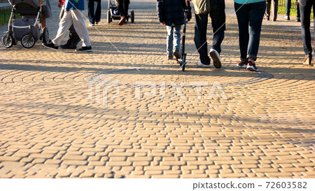 Crowd of people are walking in the park. 72603582